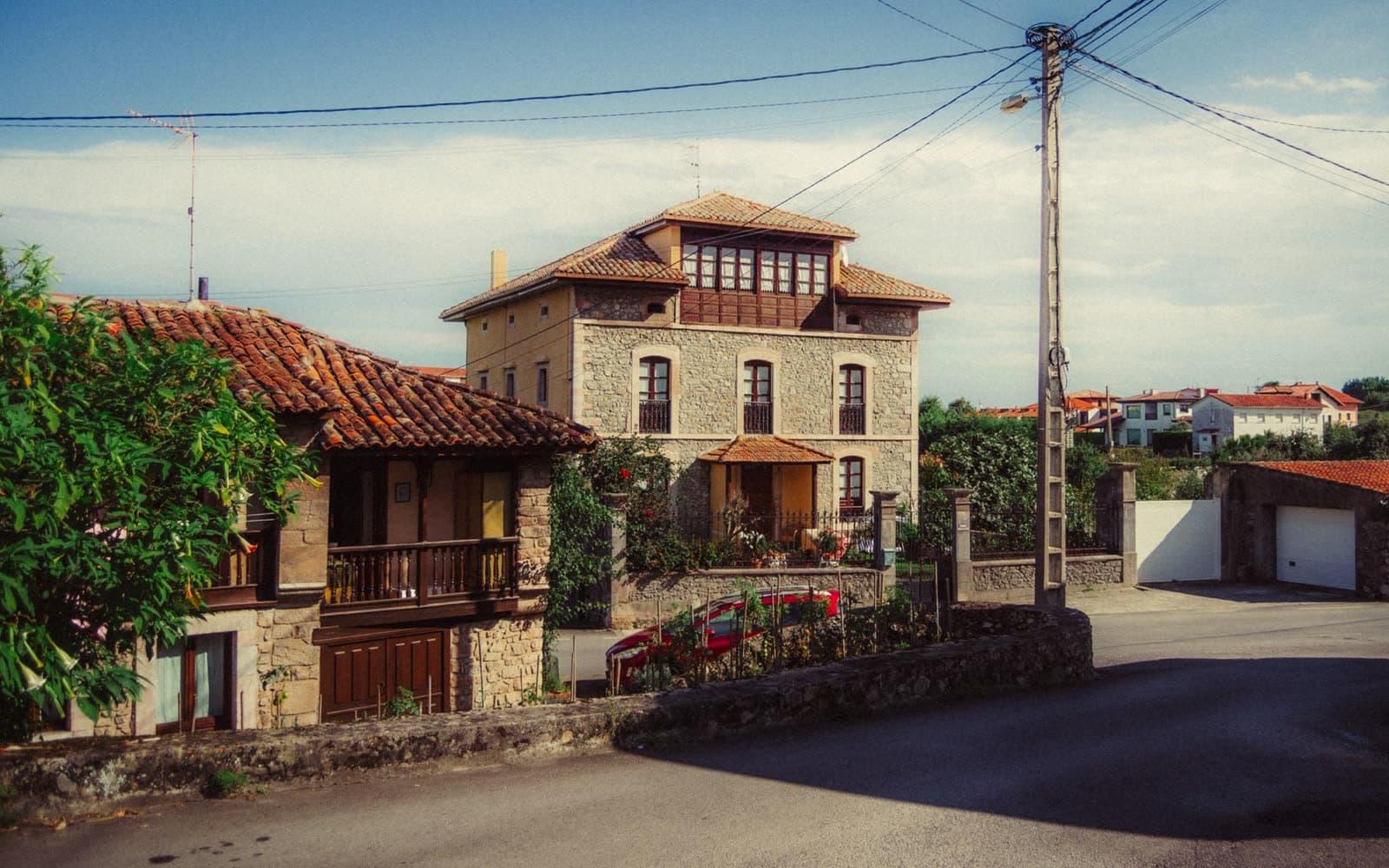 Casa de piedra de tres plantas con una galería acristalada de madera en el ático