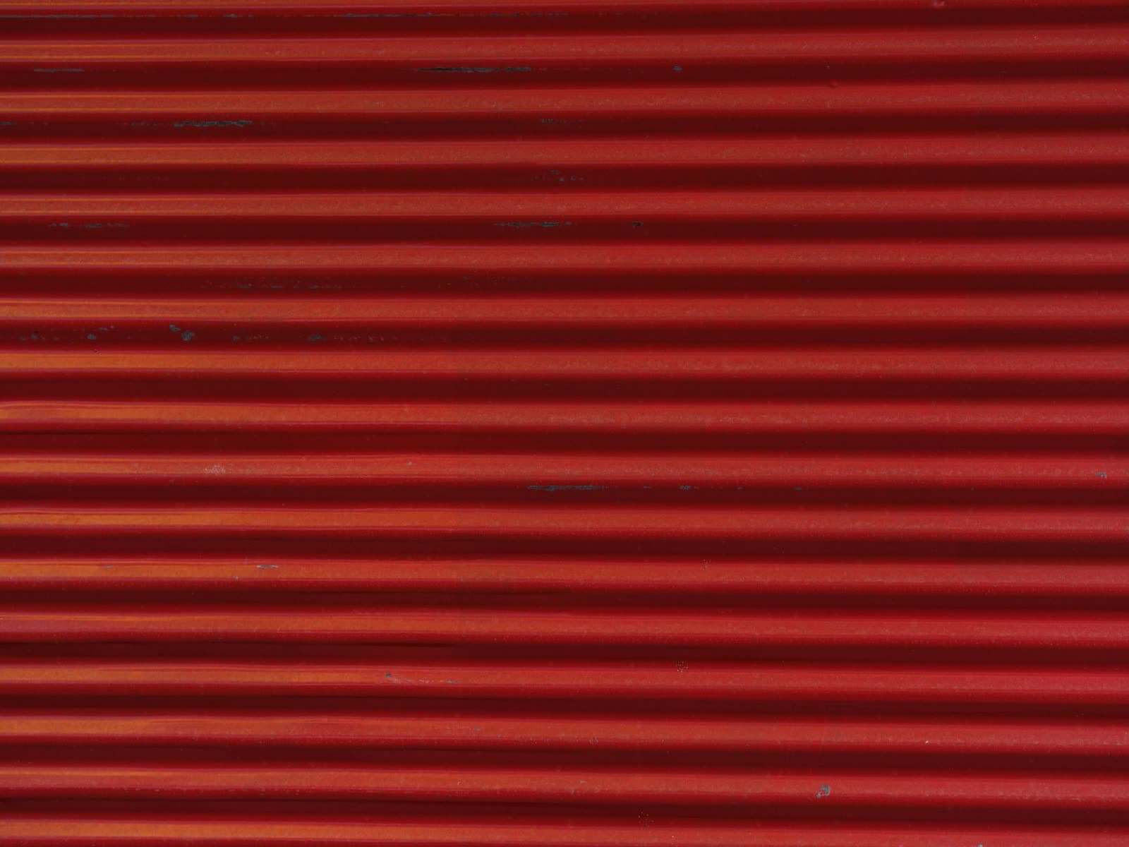 Primer plano de las lamas horizontales de un cierre metálico enrollable pintado de rojo